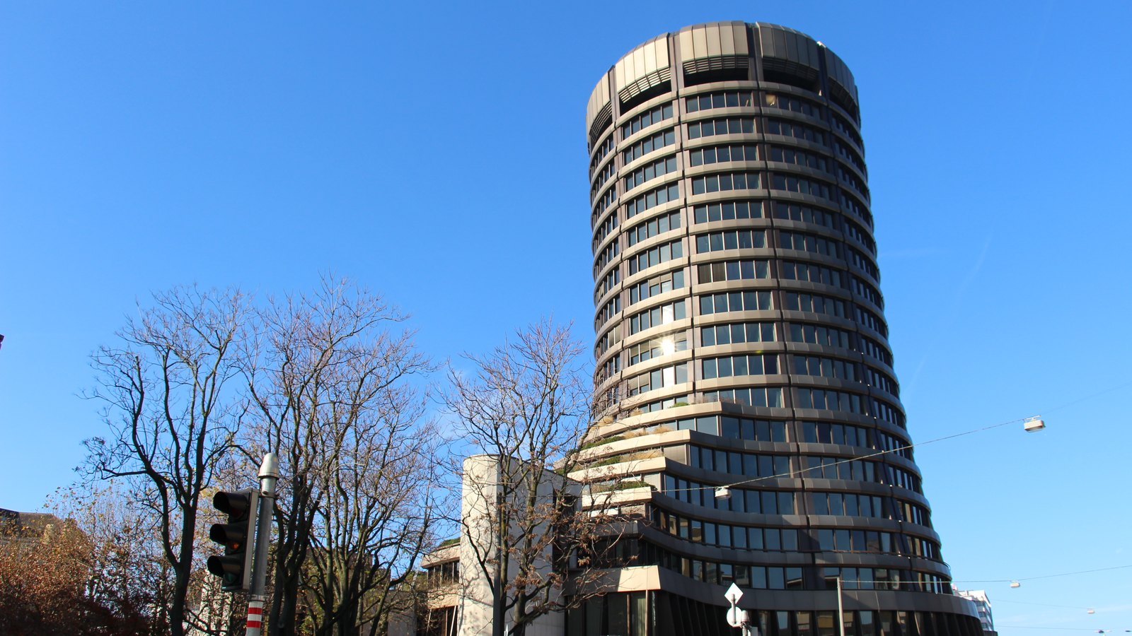 Cylindrical tower of the Bank for International Settlements against a clear blue sky
