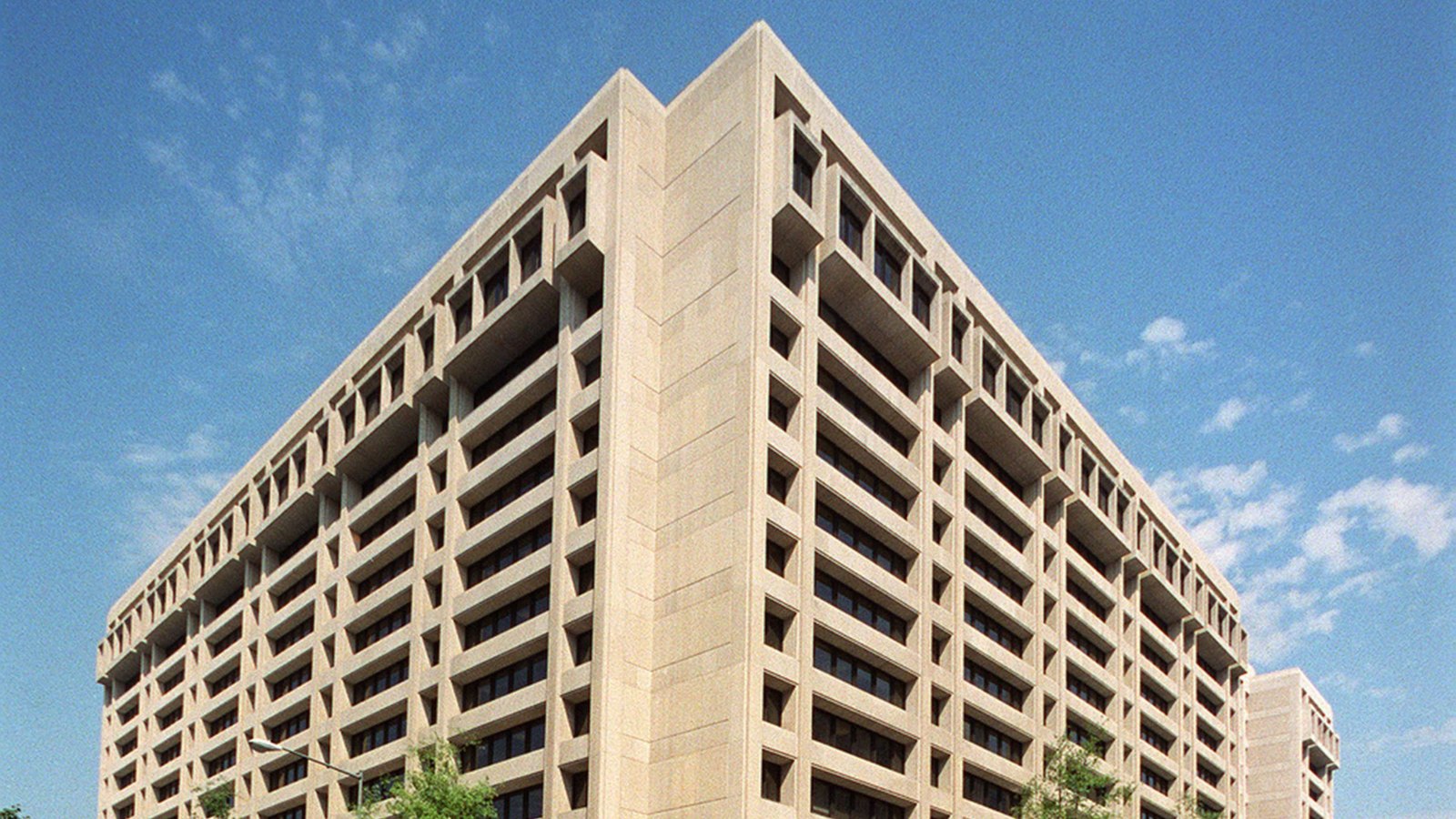 Corner view of the International Monetary Fund's stepped concrete headquarters under a blue sky