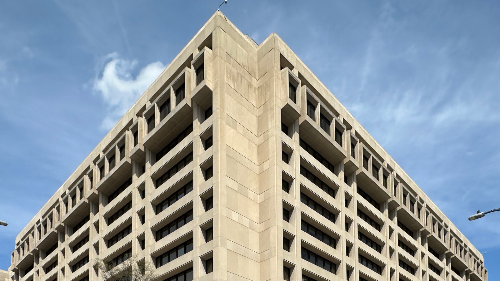 Concrete International Monetary Fund headquarters with street trees in front on a partly cloudy day