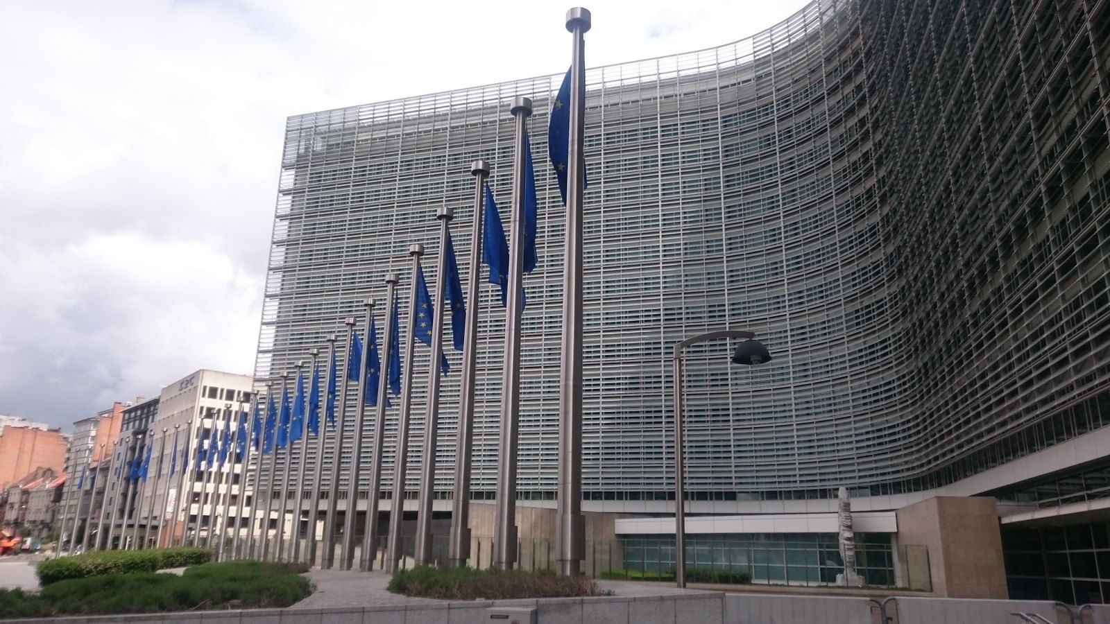 A curved glass and steel office building with a row of flags in front