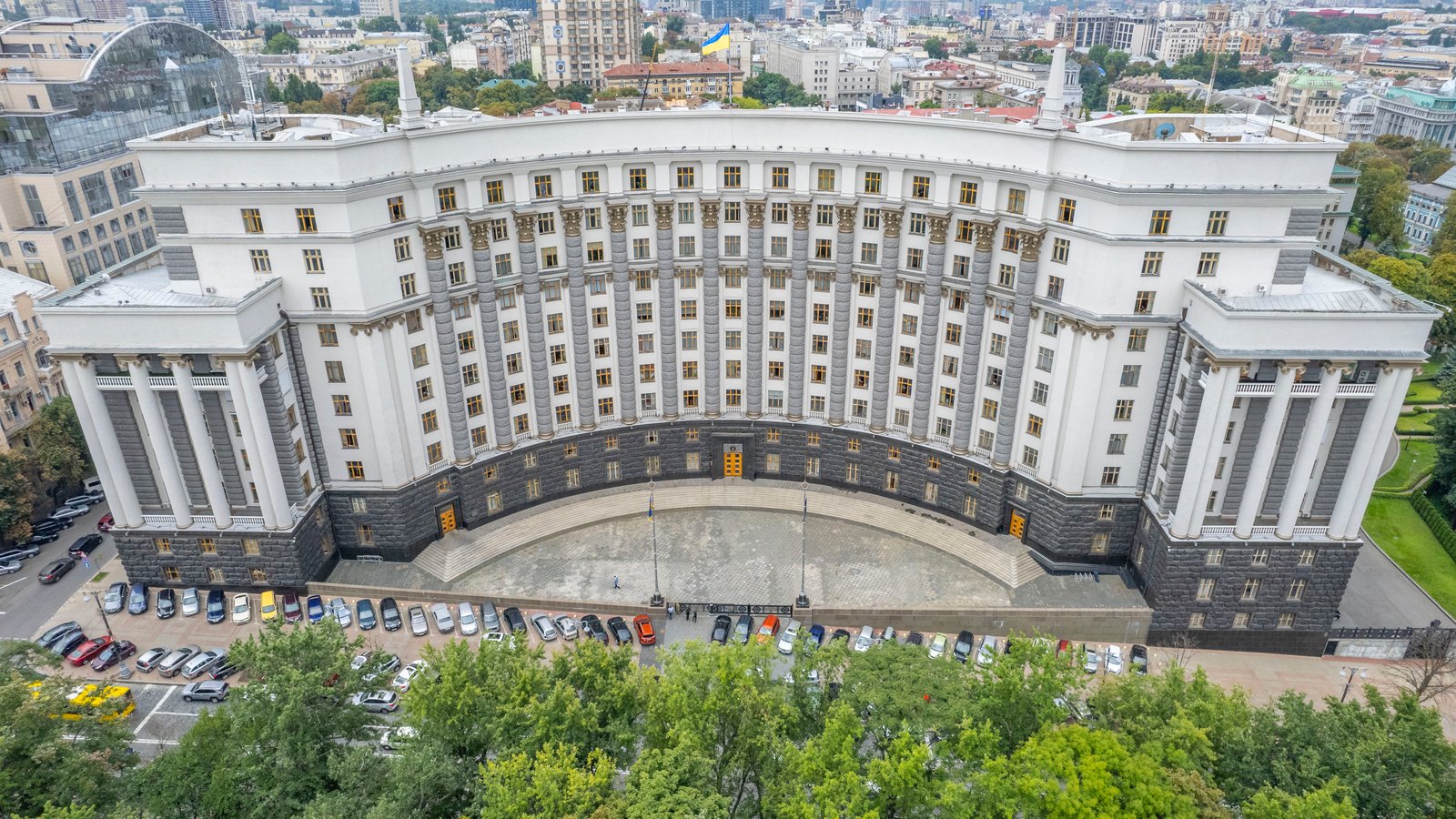 Aerial view of a massive curved government building with a columned facade among trees