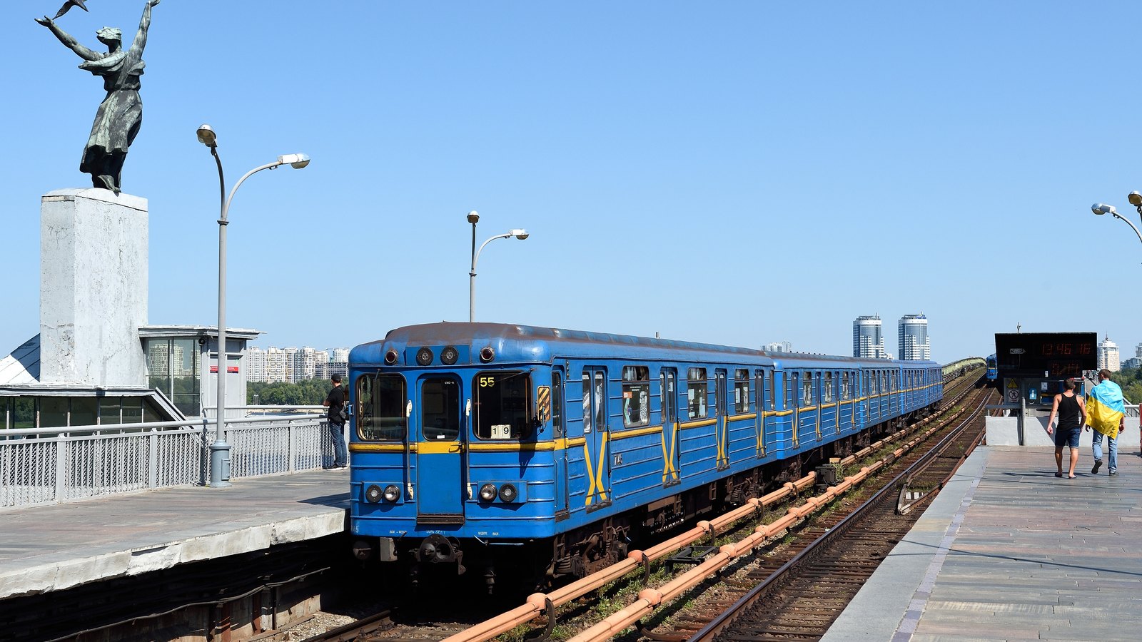 A blue metro train standing at an open-air station platform