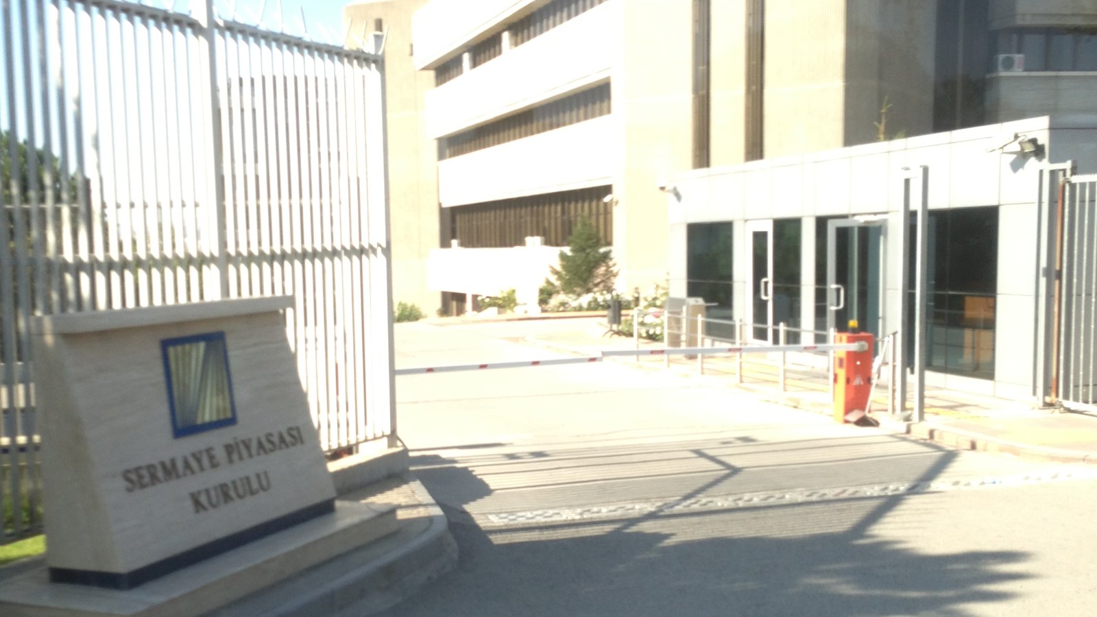 A concrete office building behind a gate, with a stone sign reading Sermaye Piyasası Kurulu in front
