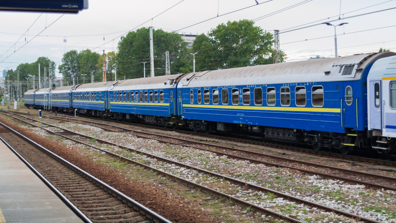Blue and white passenger sleeping cars standing at a railway station platform