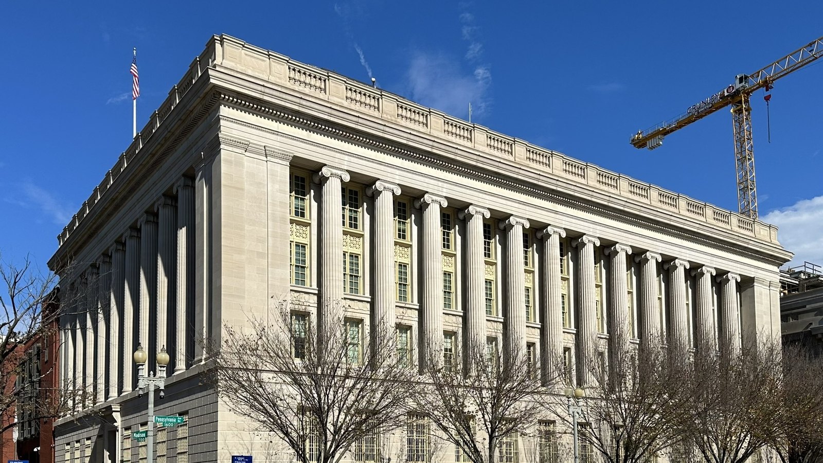 A neoclassical stone building with tall columns on a street corner