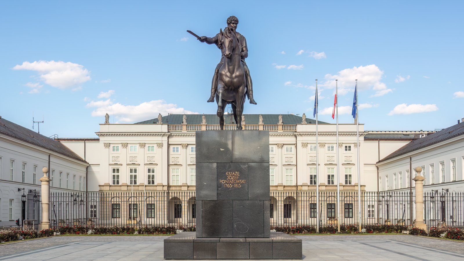 A classical palace with a columned portico behind an equestrian statue on a wide forecourt