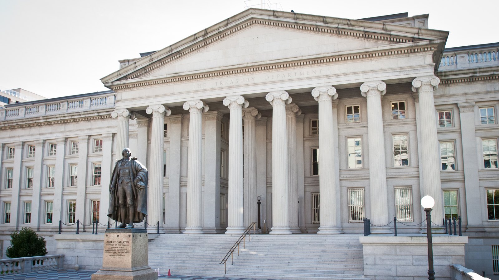Columned portico of the Treasury Building with a bronze statue on a pedestal in a chequered forecourt